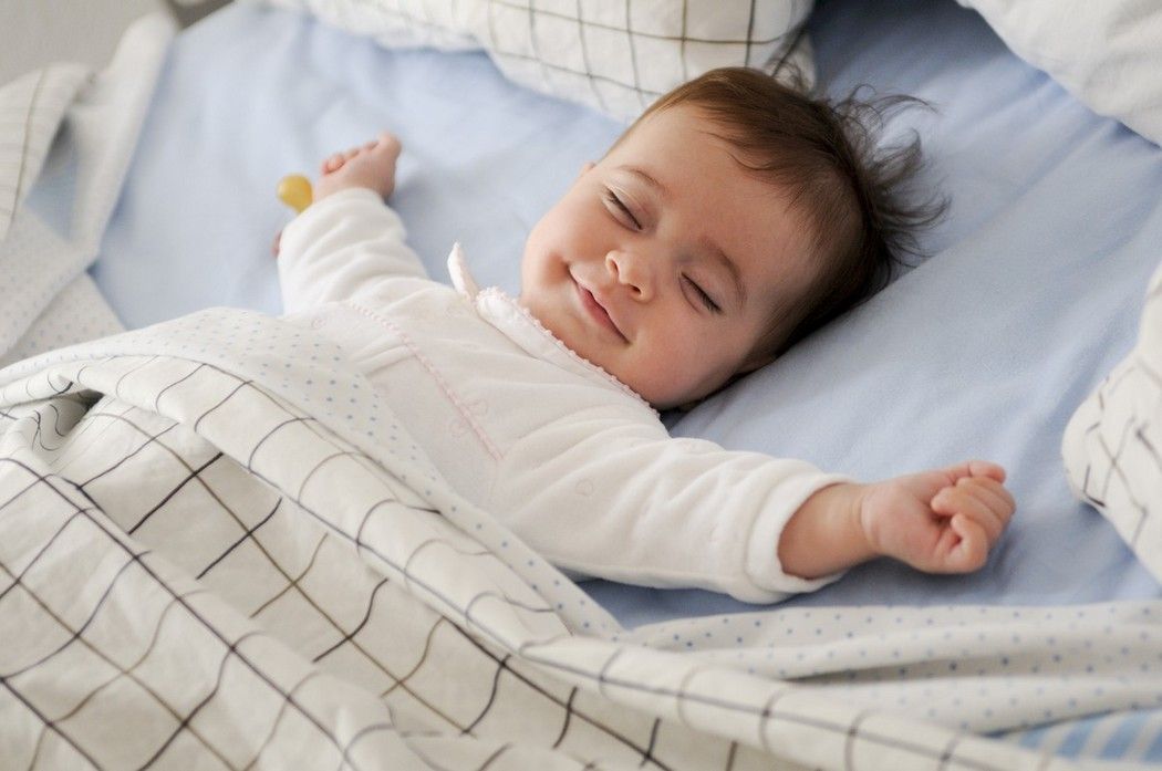 Wach im Bett liegendes Baby am Abend