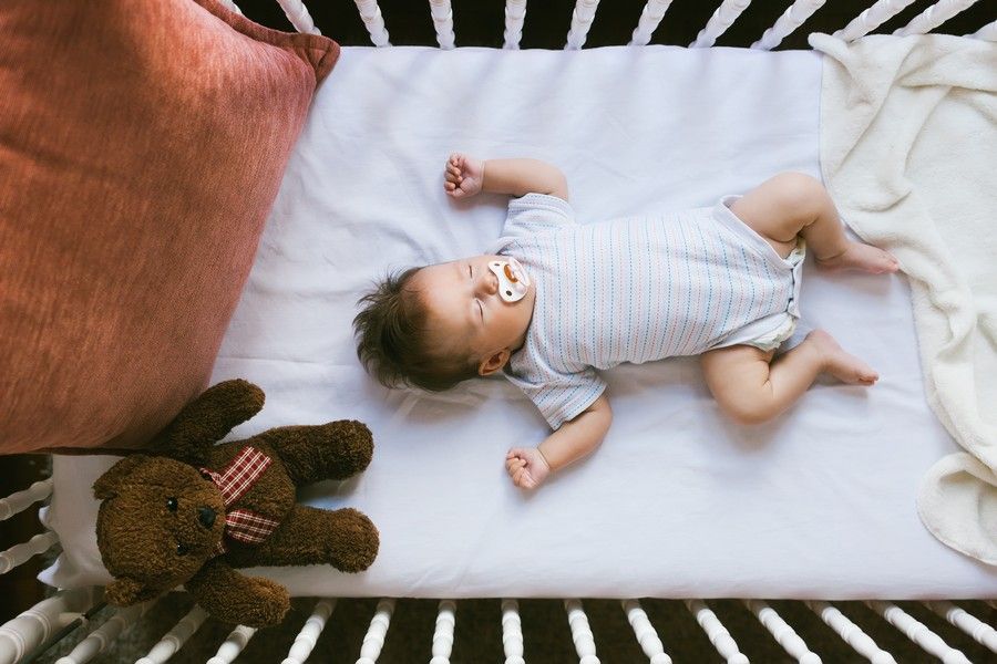 Baby schl&auml;ft auf dem R&uuml;cken in seinem Bett