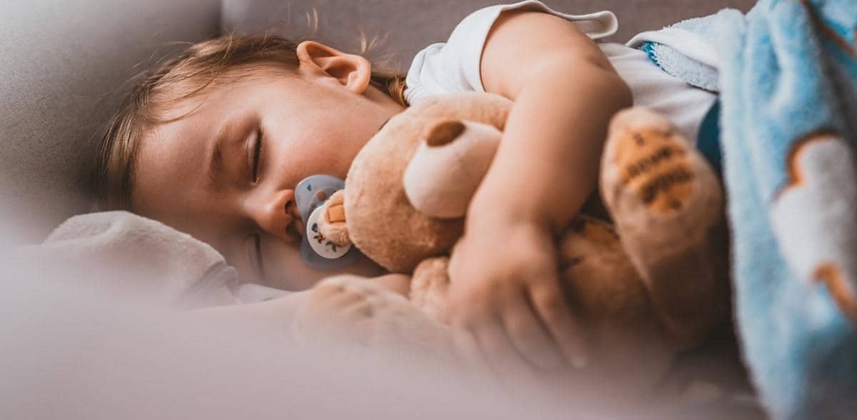 Schlafendes Baby, daneben ein Lautsprecher in sicherem Abstand zum Bett